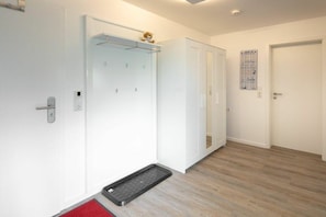 Ein Hotelzimmer mit Dusche, einer Tür mit Handtuchhalter und einer roten Matte im Eingangsbereich.