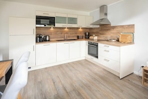 Eine moderne Küche mit weißen Schränken, einer Holz Arbeitsplatte und einem eingebauten Backofen.