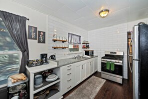A compact kitchen with white cabinets, a built-in oven, and a refrigerator. - PET FRIENDLY Boulder Bay Retreat with HOT TUB Under the Pines, Remodeled Kitchen, Multiple Decks, Outdoor Games & Cozy Mountain Charm! (Big Bear Lake)
