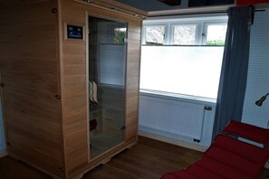 Ein Zimmer mit einem Holzkasten, einem Fenster mit Blick und einem roten Sessel.