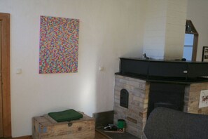 Ein Zimmer mit Kamin, einer Holzkiste und einem farbenfrohen, abstrakten Gemälde an der Wand.