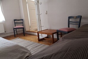 A room with a bed, two chairs, a wooden table, a coat rack, and a door. - Holiday apartment with 2 bedrooms (Groß Zecher)