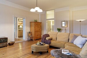 A living room with a sofa, ottoman, wooden cabinet, and a lamp. - Holiday apartment with 2 bedrooms (Groß Zecher)