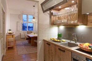 A modern kitchen with wooden cabinets, a built-in oven, and a window overlooking a snowy landscape. - Holiday apartment with 2 bedrooms (Groß Zecher)