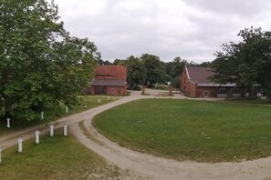 Een landelijke omgeving met een gebouw van baksteen, een grasveld en een onverharde pad.