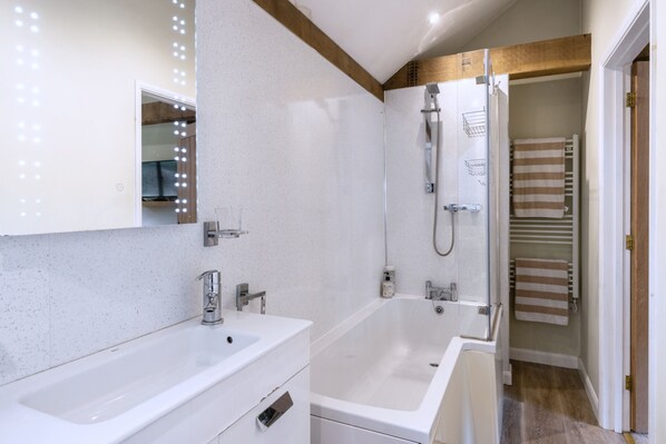 Een moderne badkamer met een dubbele wastafel, een douche en een spiegel met verlichting.