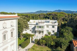 A large, white, multi-story building with a balcony and a well-maintained garden. - Villa Bianca, just a few steps from the ocean, with an exclusive garden and hot tub (Livorno)