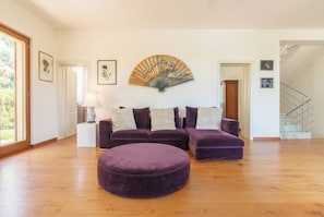 A spacious living room with a sectional sofa, a round ottoman, and a fan on the wall. - Villa Bianca, just a few steps from the ocean, with an exclusive garden and hot tub (Livorno)