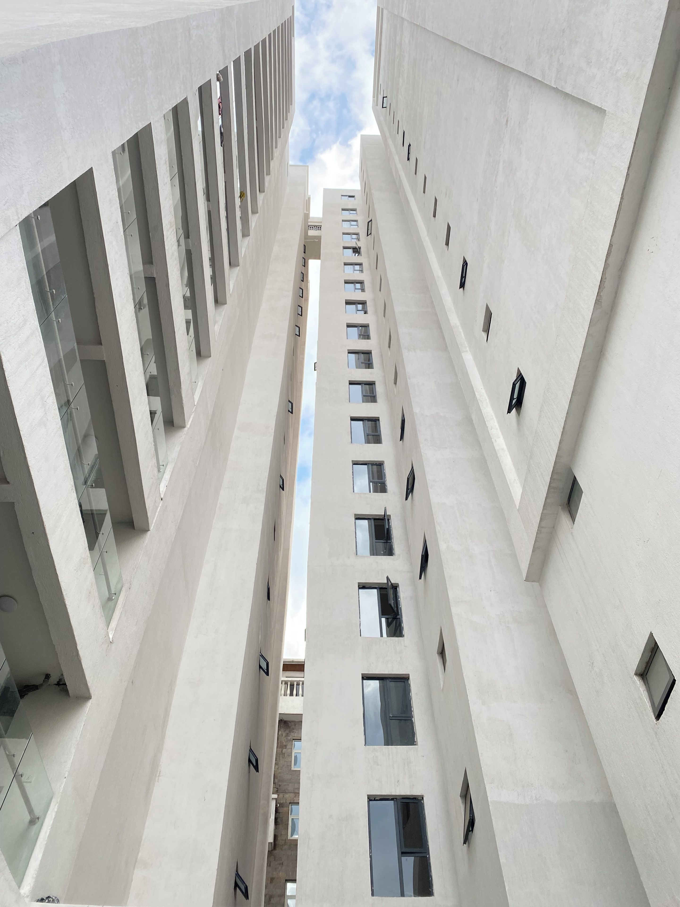 A modern building with a central atrium, multiple floors, and a clear sky view.
