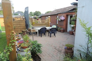 A patio with a table and chairs, surrounded by potted plants and a wooden fence. - Holiday apartment with 1 bedroom (Tönning)