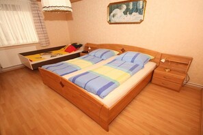 A bedroom with a wooden bed, a bedside table, a nightstand, and a window with curtains. - Holiday home in Dunum with swimming pool (Dunum)