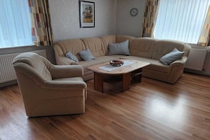 A living room with a beige sofa, a wooden coffee table, and a single armchair. - Holiday home in Dunum with swimming pool (Dunum)