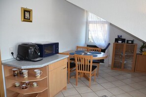 A small kitchenette with a coffee maker, microwave, and a dining area with a table and chairs. - Holiday apartment Mellum (Horumersiel)