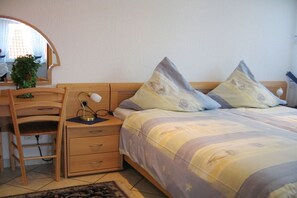 A bedroom with a bed, a desk, a chair, and a bedside table. - Holiday apartment Mellum (Horumersiel)