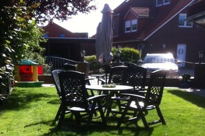 A patio with outdoor seating, a small play area, and a house in the background. - Holiday apartment Mellum (Horumersiel)