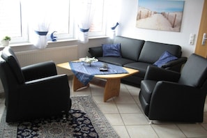 A living room with a sofa, two armchairs, a coffee table, and a rug. - Holiday apartment Mellum (Horumersiel)