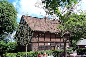 Un bâtiment traditionnel avec un toit en tuiles et des murs en briques, entouré de verdure.
