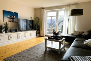 Un salon équipé d’un téléviseur, d’un canapé, d’une table basse et offrant une vue sur l’extérieur grâce à une grande fenêtre.