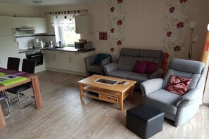 A compact living space with a kitchenette, a sofa, a dining table, and a coffee table. - Holiday apartment with 2 bedrooms (Aurich\/ Tannenhausen)