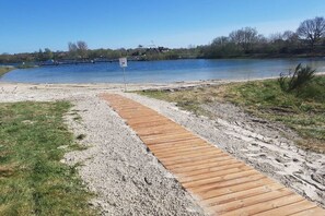 A wooden boardwalk leading to a body of water with a sign indicating a boat launch area. - Holiday apartment with 2 bedrooms (Aurich\/ Tannenhausen)