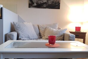 Ein modernes Wohnzimmer mit einem Glastisch, einer roten Tasse und einer Lampe auf einem Holznachttisch.