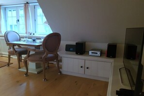 Ein Zimmer mit einem Holzespeisetisch, zwei Stühlen, einem weißen Schrank und einem Fernseher.