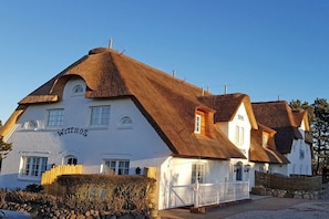 Ein traditionelles Gebäude mit einem Reetdach, weißen Wänden und einem Schild mit der Aufschrift 'Withus'.
