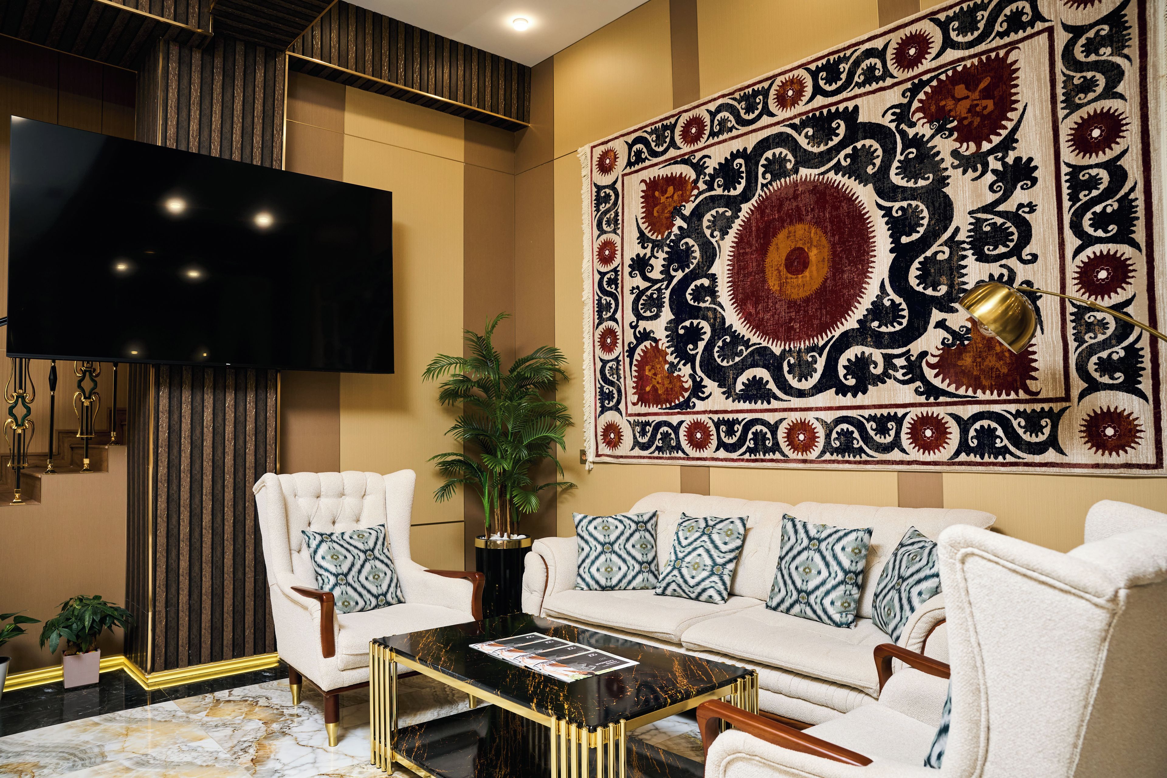 A modern living room with a large flat-screen TV, a patterned rug, a sofa with patterned cushions, and a coffee table.