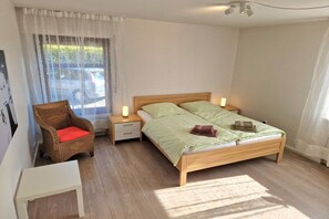 A bedroom with a bed, nightstands, a chair, and a small table. - Guesthouse "Wangerland" (Horumersiel)