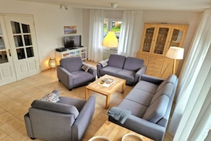 En stue med grå sofaer, et træbord, et fjernsyn og et skab.