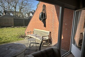 Un espace patio avec un banc et une table, un mur en briques et un objet suspendu.