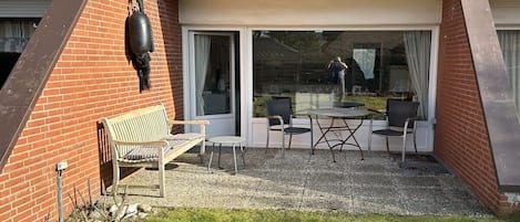 A patio with a table and chairs, a bench, and a hanging decoration.