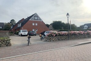 Un quartier résidentiel avec une maison, des voitures garées et un vélo.