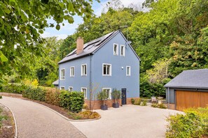 A two-story house with a blue exterior, a brick chimney, and a garage. - The Blue Barn (Tunbridge Wells)