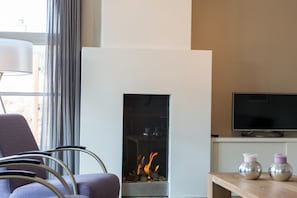 Ein modernes Wohnzimmer mit Kamin, Fernseher und einer Sitzecke.