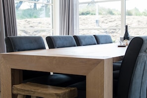 Ein Konferenztisch mit sechs Stühlen, einer Weinflasche und einem Glas darauf.