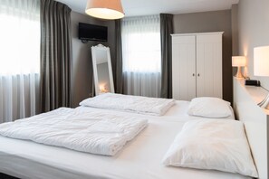 Ein Hotelzimmer mit Bett, Kleiderschrank, Fernseher und Lampe.
