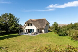 Ein Haus mit geneigtem Dach, einer Veranda und einem Rasen.