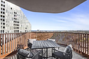 Ein Balkon mit Tisch und Stühlen mit Blick auf eine Stadtlandschaft.