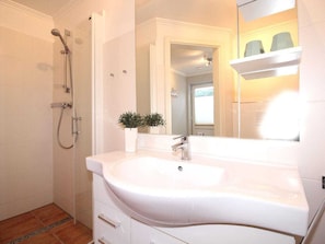 A bathroom with a white sink, a handheld showerhead, and a small potted plant. - Holiday Apartment in Sylt With 2 Bedrooms (Sylt)