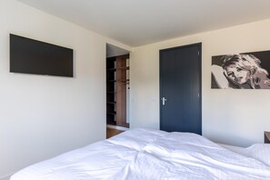 Ein Schlafzimmer mit einem Bett, einem Kleiderschrank und einer Tür zu einem Abstellraum.