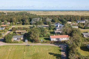 A residential area with houses, a grassy field, and a view of the ocean. - Charming bungalow on Ameland with a beautiful garden (Ballum)