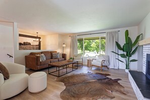 Ein Wohnzimmer mit braunem Ledersofa, einem weißen Sessel, einem Couchtisch und einem großen Lederteppich.
