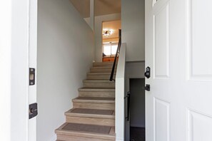 Eine Treppe führt zu einer Zwischenebene mit einer Tür rechts und einem Fenster im Hintergrund.