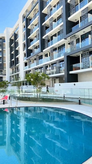 A modern building with multiple balconies and a swimming pool. - Vanilla Homes Premium 2BR in Masdar City (Abu Dhabi)