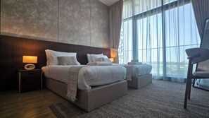 A modern hotel bedroom with a large bed, bedside tables, a chair, and a view through large windows. - Vanilla Homes Premium 2BR in Masdar City (Abu Dhabi)