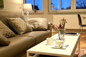 Ein modernes Wohnzimmer mit einer Couch, einem Couchtisch, einer Vase mit Blumen und einer Lampe.