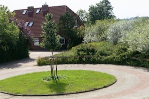 Een woonhuis met een verharde oprit, gazon en houten omheining.