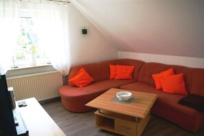 Een moderne woonkamer met een hoekbank, een houten salontafel en een televisie.