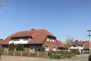 A residential building with a red-tiled roof, multiple windows, and a gated entrance. - Baltrum at the "Kogge" house (Norden-Norddeich)